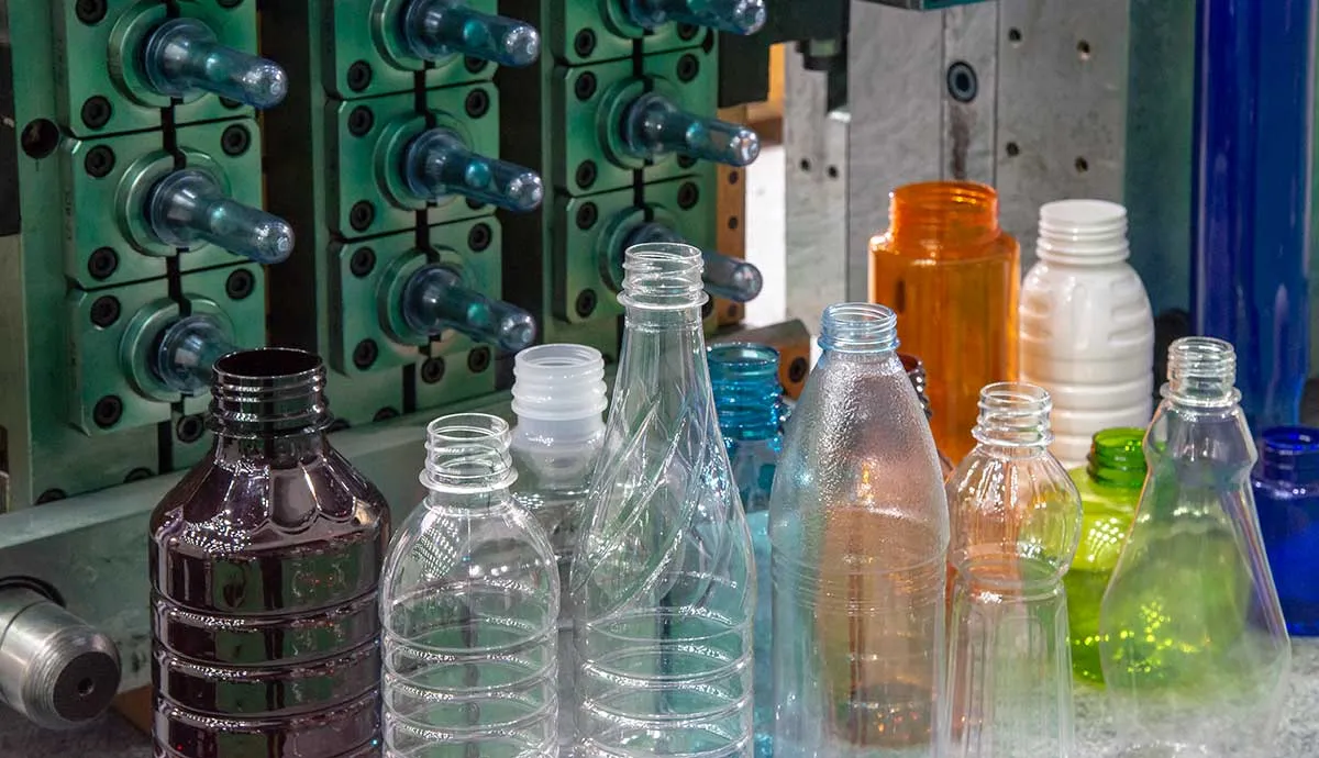 The plastic bottles and injection mold in background. PET plastic bottle manufacturing concept.